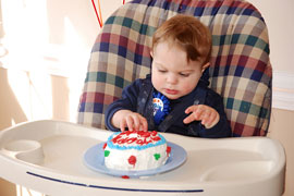 baby in high chair with birthday cake